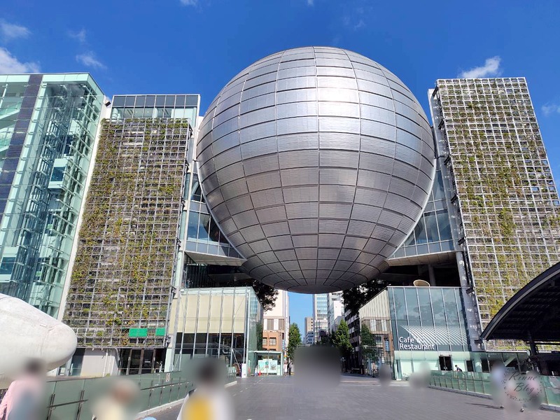 銀色の球体を中心に、緑の壁の建物が並ぶFUJIなごや科学館の外観