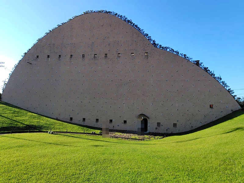 芝生の斜面の先に建つ、土の山のようなモザイクタイルミュージアム