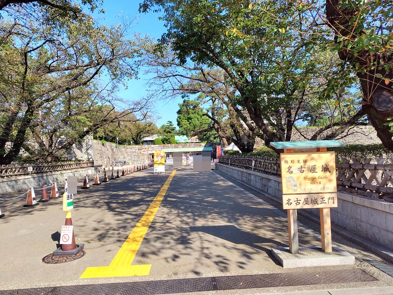 「名古屋城」の木の看板が立つ正門への道